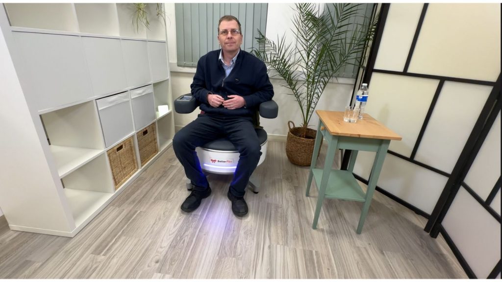 Patient sitting on pelvic floor treatment chair during non-invasive therapy session in derby at quality studio and academy